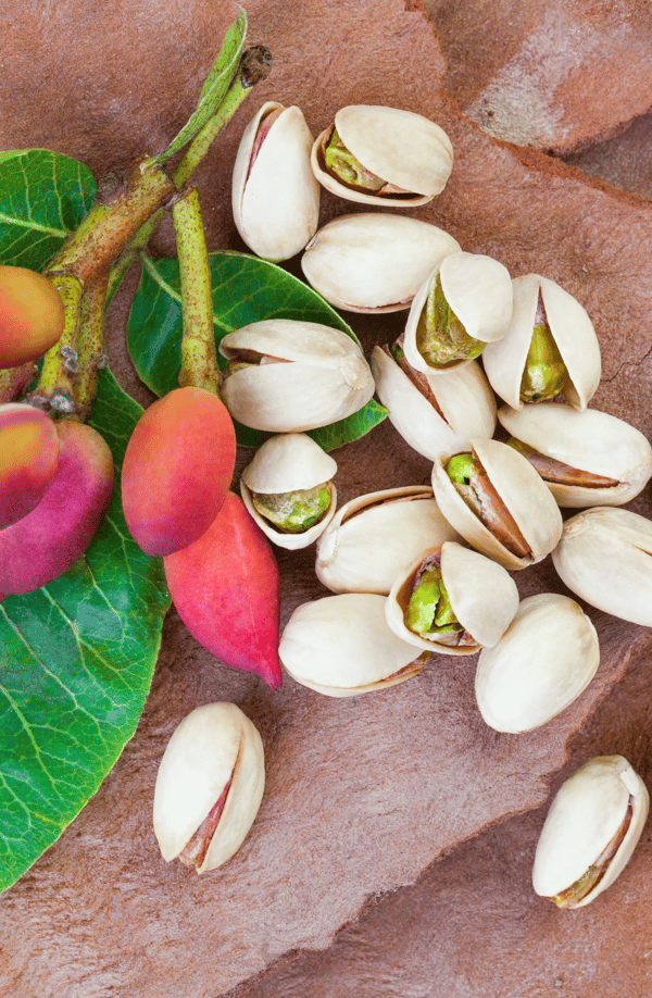 Unripe pistachios and pistachios in shells on a textured surface.